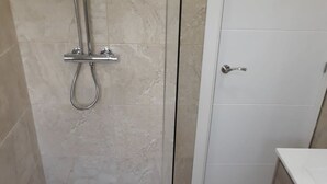 Et badeværelse med bruser, toilet og håndvask.