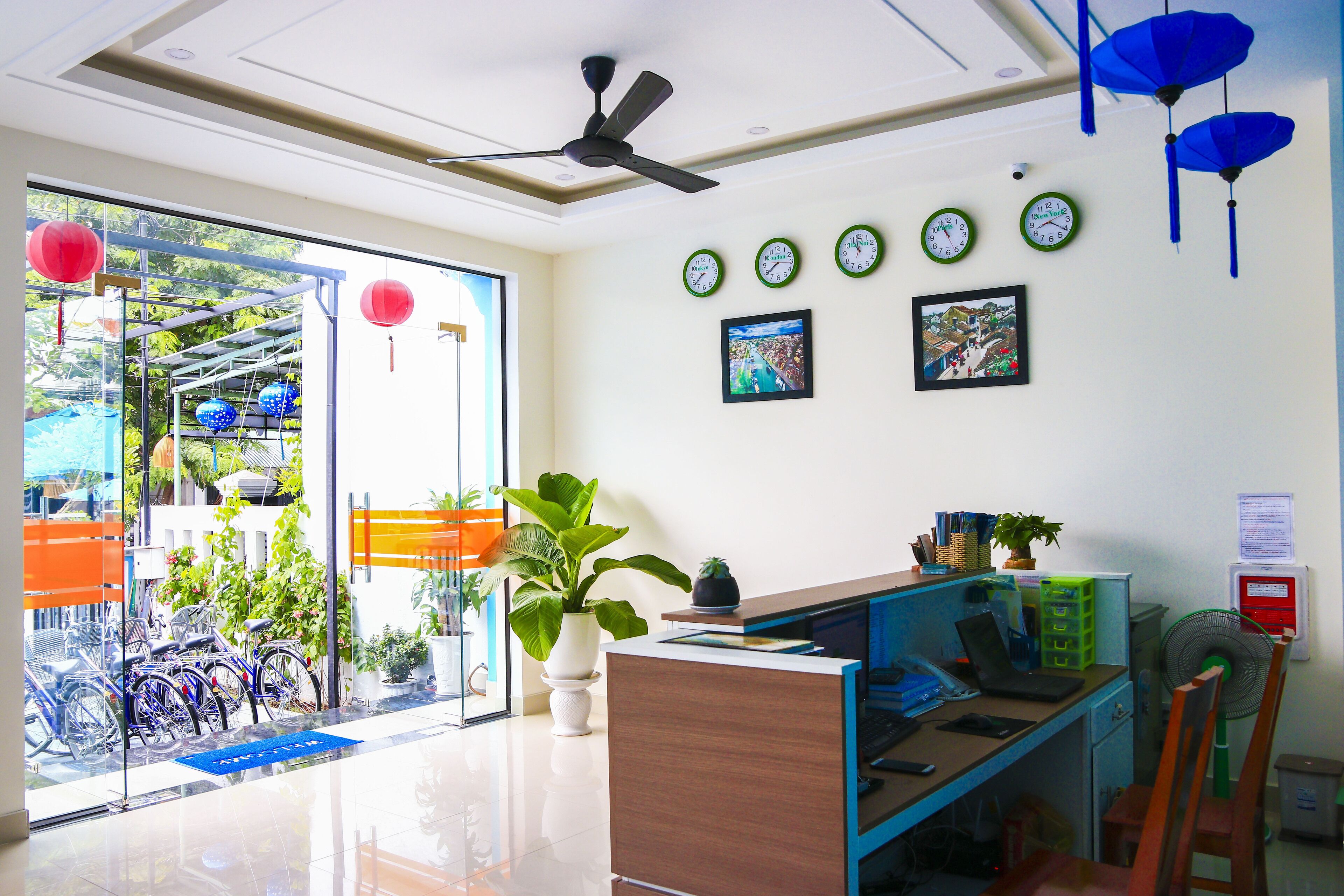 Espaço de escritório moderno com balcão de recepção, vários relógios e ventilador de teto.
