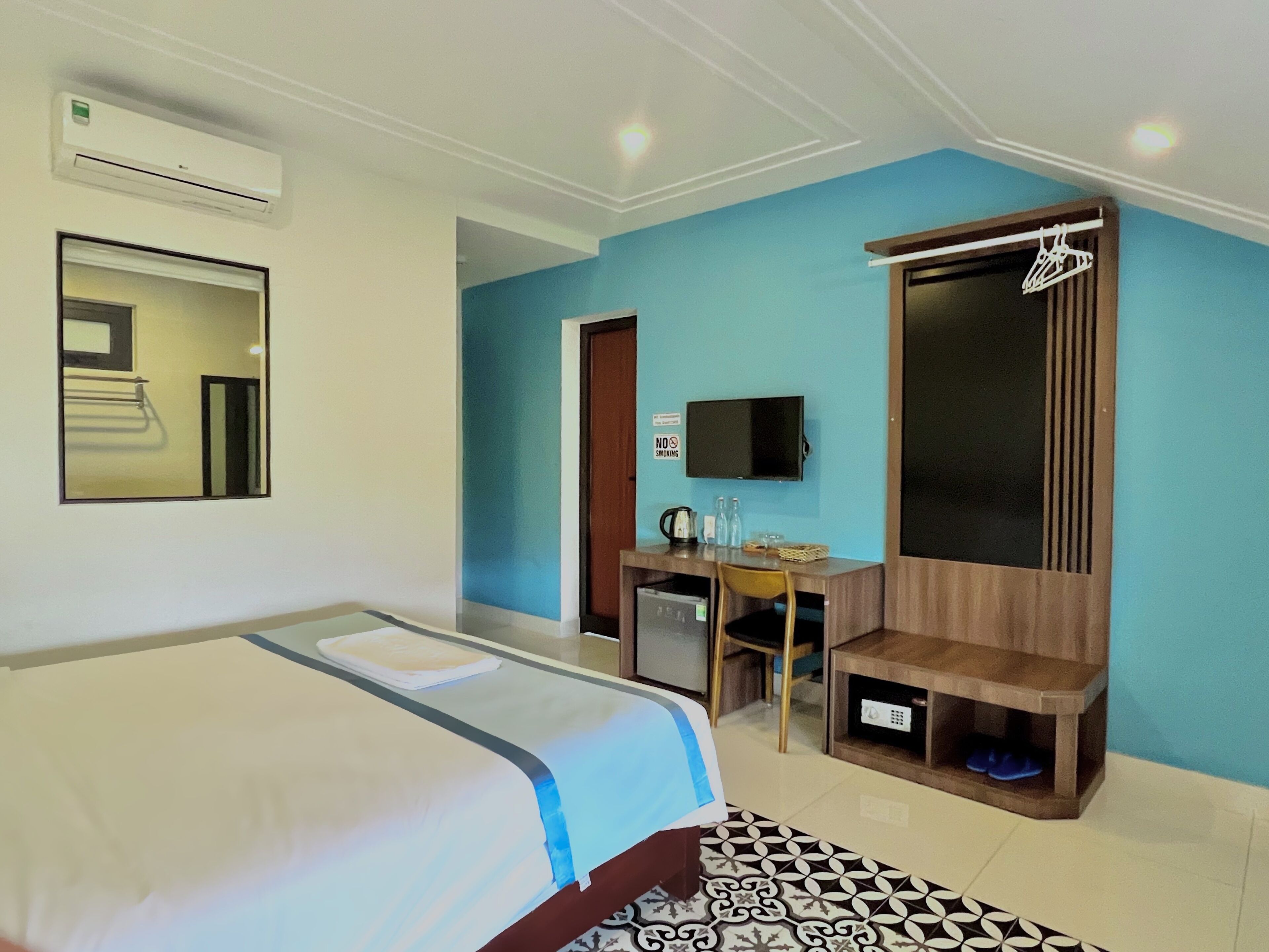 Une chambre d’hôtel équipée d’un lit, d’un bureau, d’une télévision et d’une armoire.