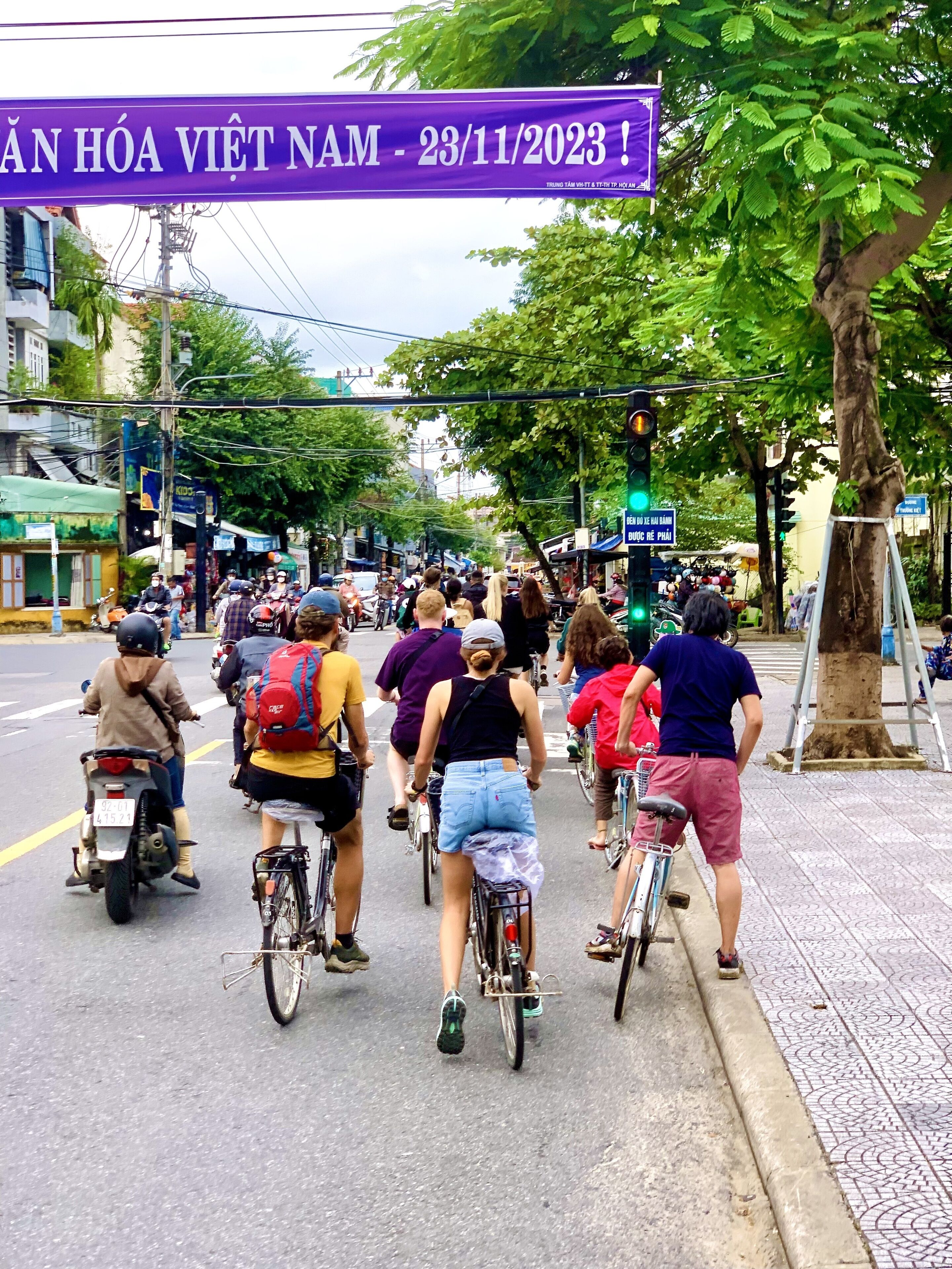 Scena di strada con un gruppo di persone che vanno in bicicletta e in moto.