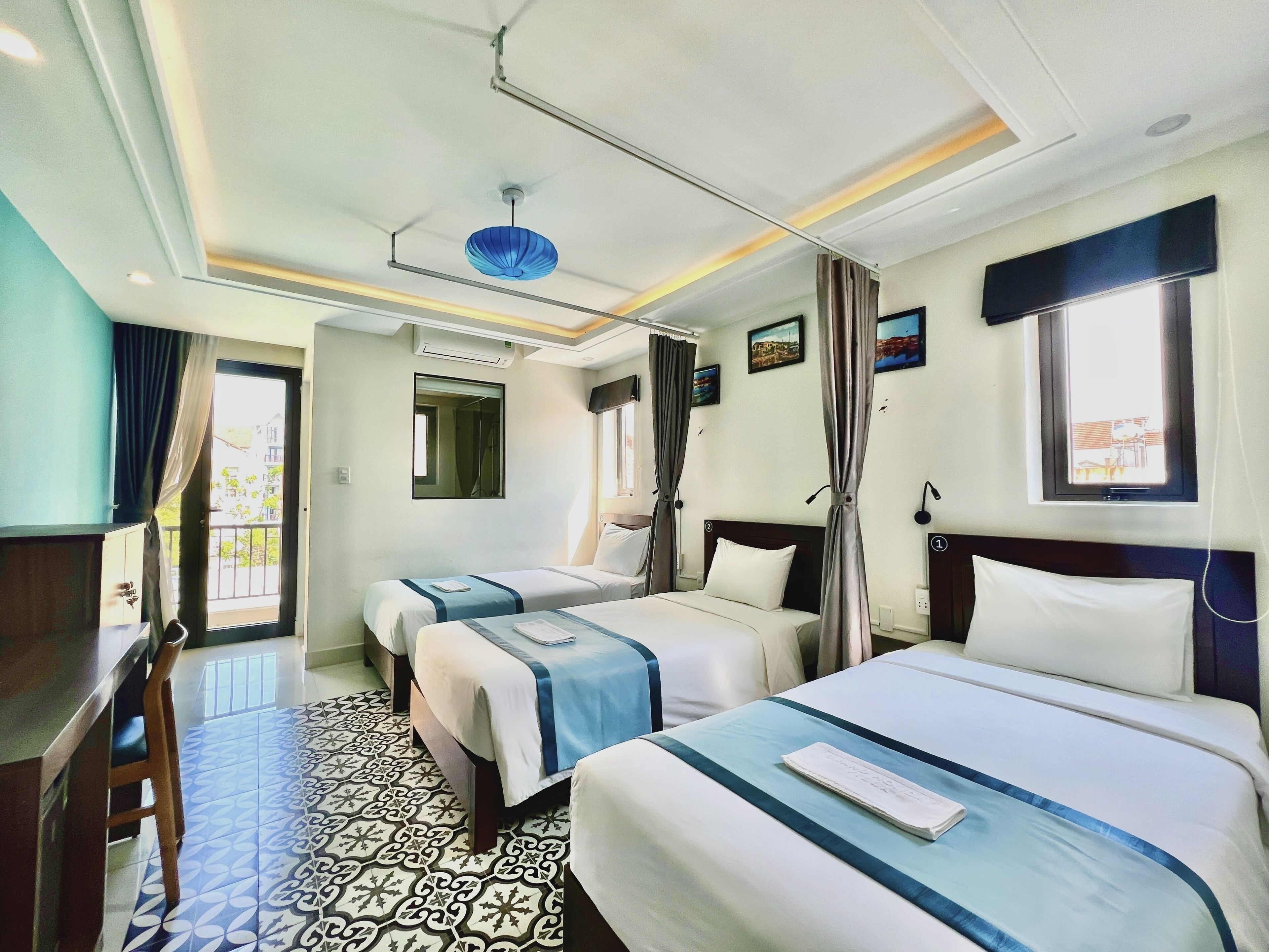 A hotel room with two beds, a desk, a mirror, and a window with curtains.