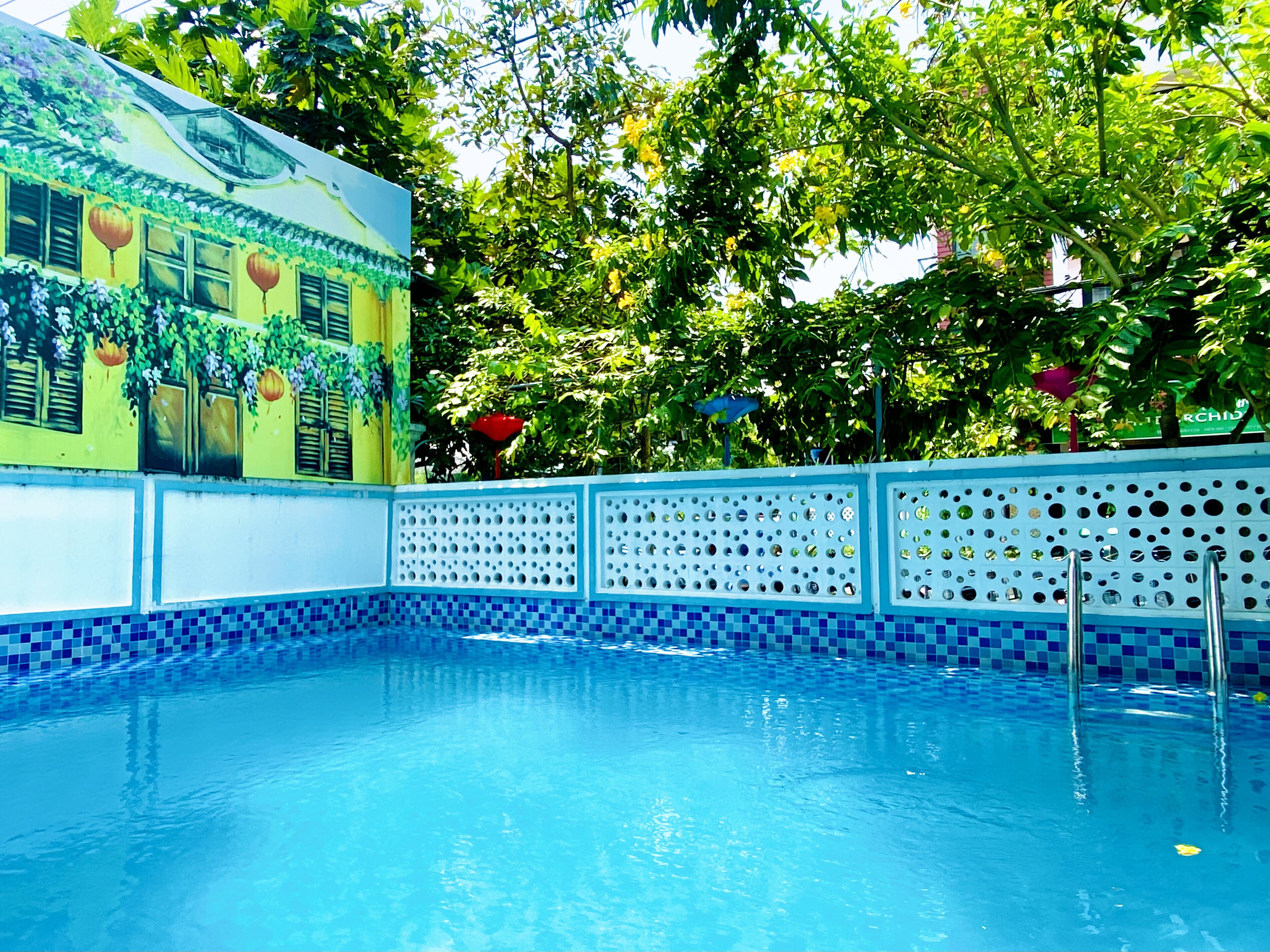 A swimming pool with blue tiled edges and a decorative fence with circular cutouts.