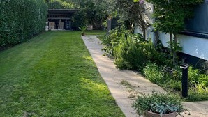 A well-maintained garden with a paved pathway leading to a building with large windows.
