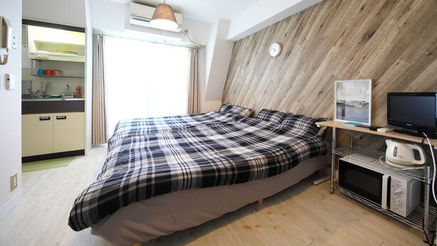 Un dormitorio con una cama, televisión, microondas y una pared de madera.