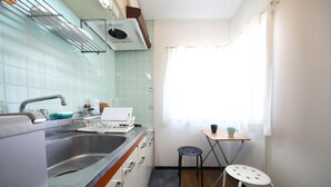 Una cocina compacta con pileta, cocina y un pequeño comedor con una mesa y dos taburetes.