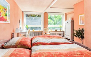 A bedroom with two beds, a desk, a chair, a radiator, and a window with a view of greenery. - Stunning apartment in St. Annen (St. Annen)