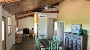 A rustic kitchen with wooden beams, a dining area with mismatched chairs, and a vintage cabinet. - Cabin 2 of 7 With Private River Access to the Nueces River (Uvalde)