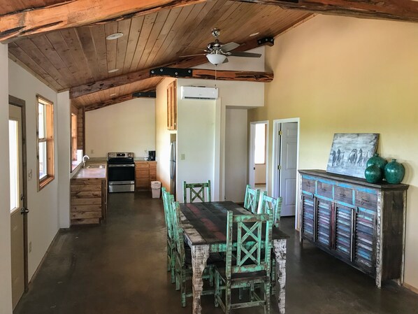 A rustic kitchen with wooden beams, a dining area with mismatched chairs, and a vintage cabinet. - Cabin 2 of 7 With Private River Access to the Nueces River (Uvalde)