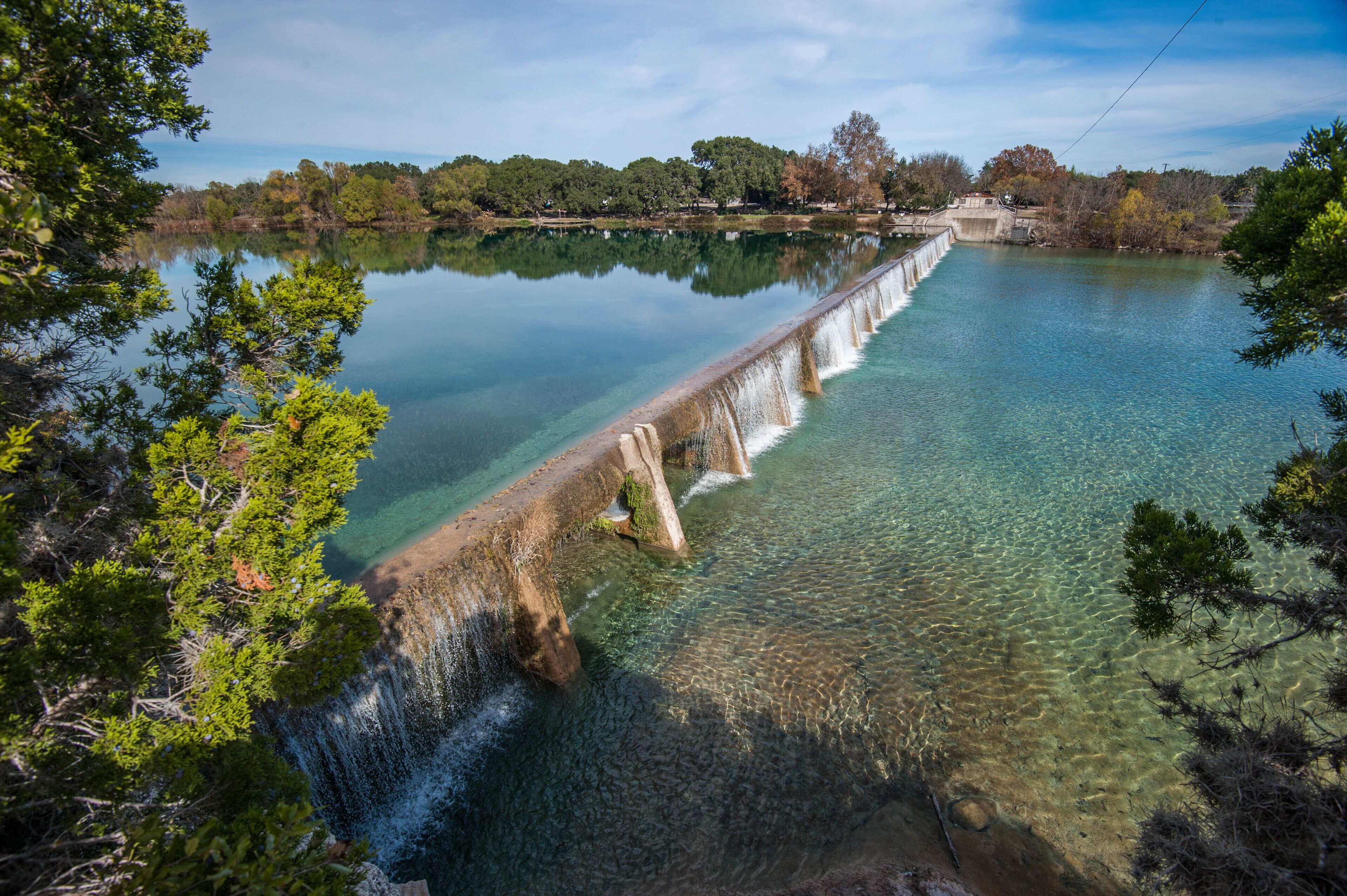 A dam with clear water and a bridge.