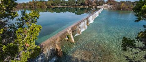 A dam with clear water and a bridge.