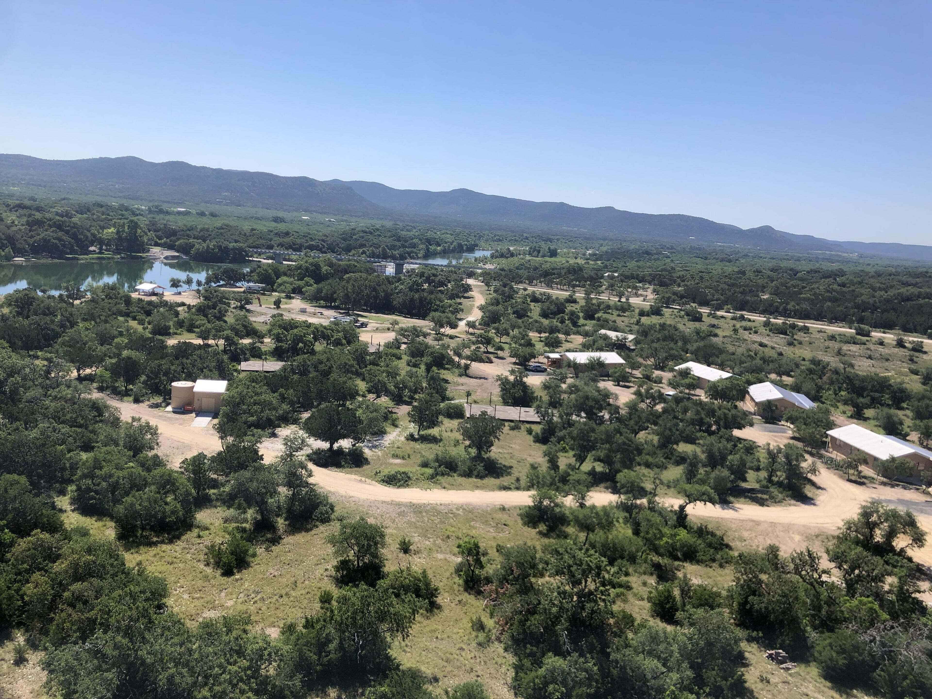 A rural landscape with scattered buildings, a lake, and mountains in the background.