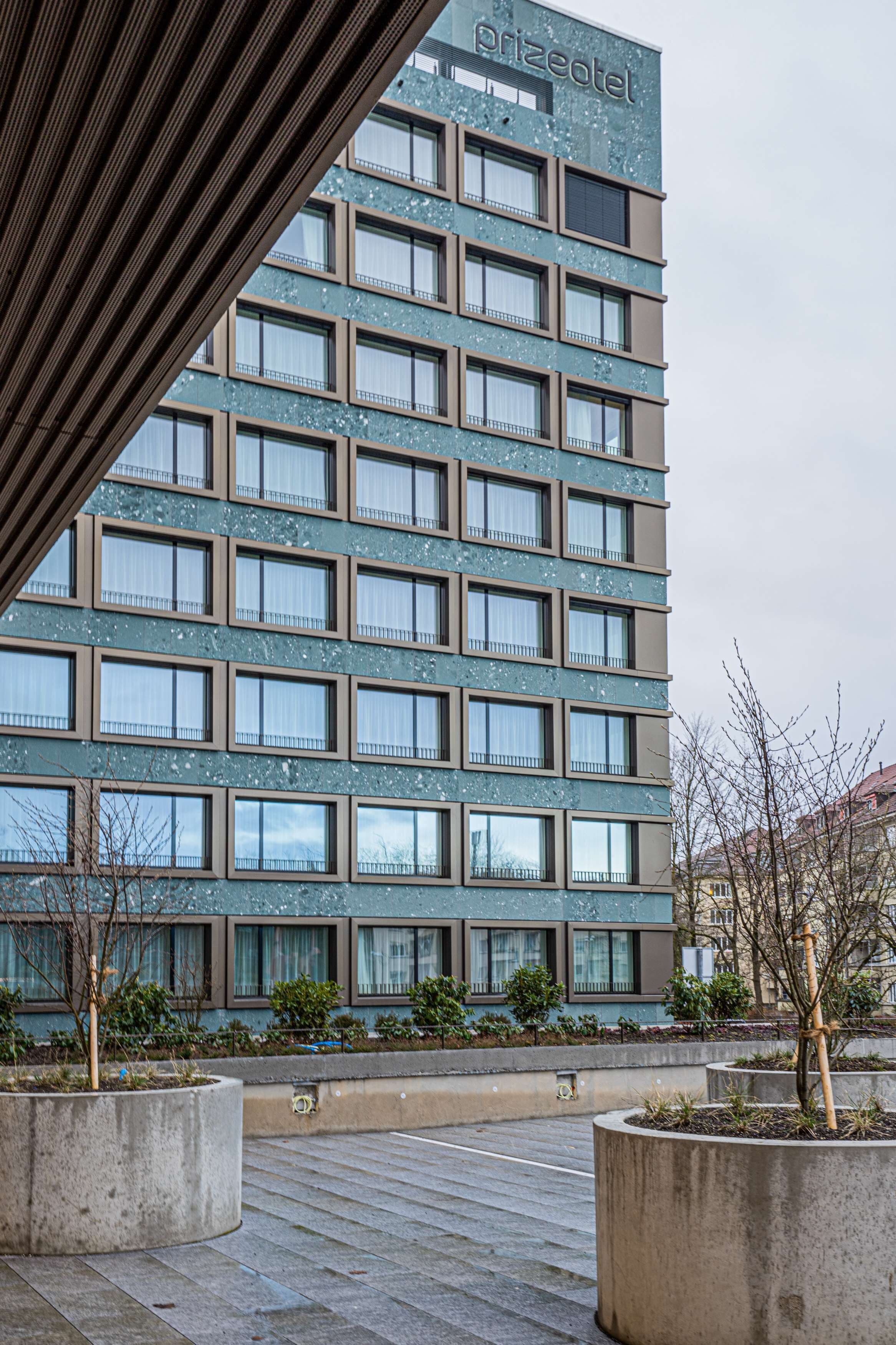 A modern hotel building with a flat facade, multiple windows, and a sign reading "prizeotel".