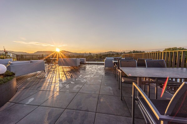 A rooftop patio with outdoor seating and a view of the sunset. - Prize by Radisson, Bern City (Bern)