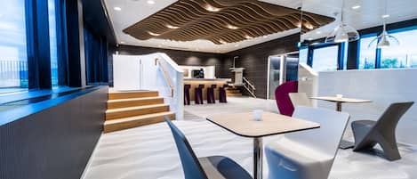 Un intérieur moderne comprenant un comptoir d’accueil, un espace salon et un escalier menant à un niveau supérieur.