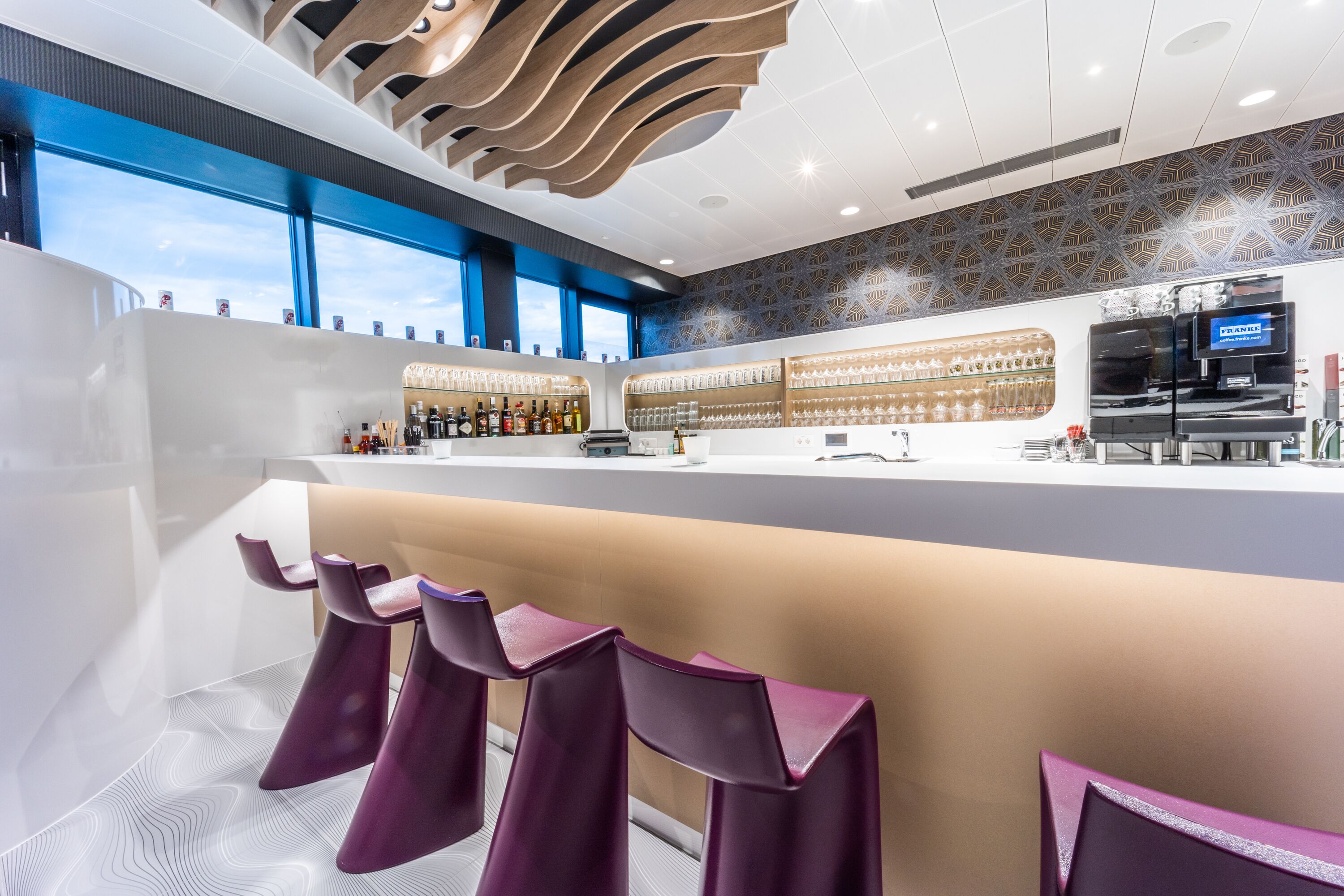 A modern bar area with a counter, bar stools, and a coffee machine.