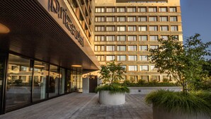 Exterior de un hotel de diseño moderno, con amplios ventanales y un patio con plantas.