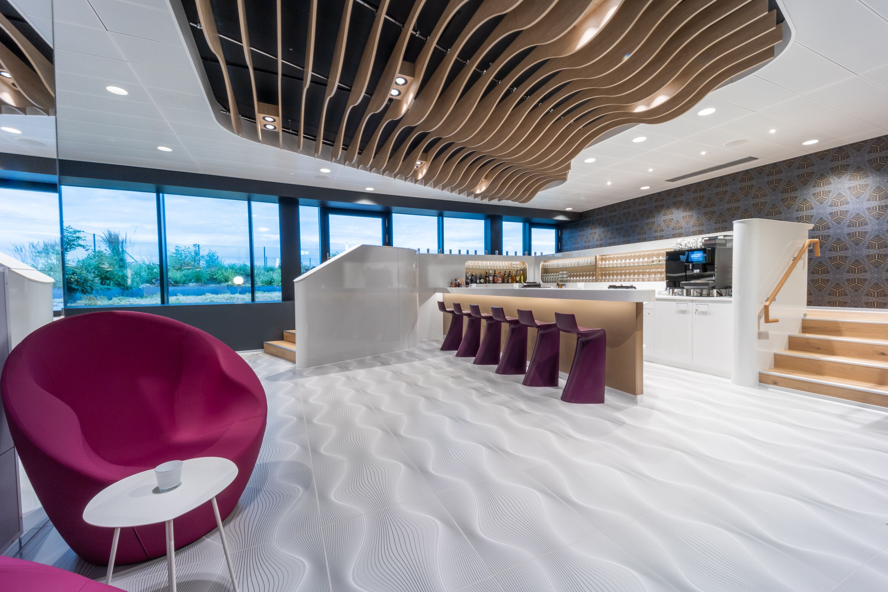 A modern interior with a bar area, seating, and a staircase.