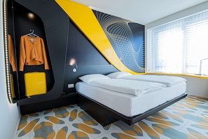 A modern hotel room with a bed, a wardrobe, and a unique wall design. - Prize by Radisson, Bern City (Bern)