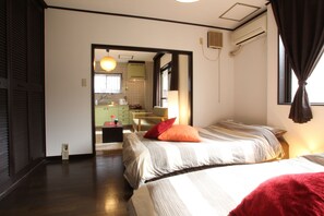 Hotellihuone, jossa on kaksi sänkyä, oleskelualue ja näkymä keittiöön.
