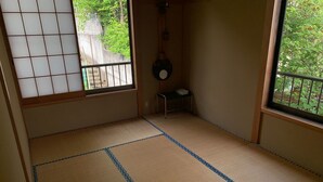 A tatami mat room with a shoji screen, a small stool, and a hanging decoration.