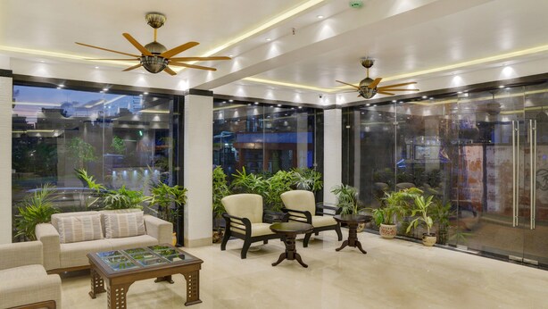 A modern lobby with seating, ceiling fans, and large windows. - Treebo Premium The Crystal, Chinar Park (Barasat)