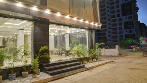 A modern building with large glass windows and a well-lit entrance. - Treebo Premium The Crystal, Chinar Park (Barasat)