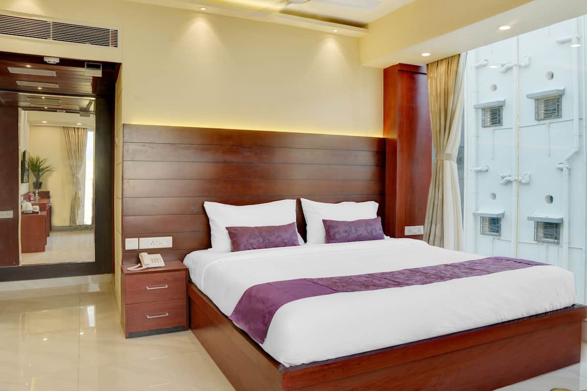 A modern hotel room with a large bed, wooden headboard, and a view of the cityscape.