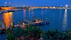 A marina with docked boats, a wooden pier, and a cityscape in the background.