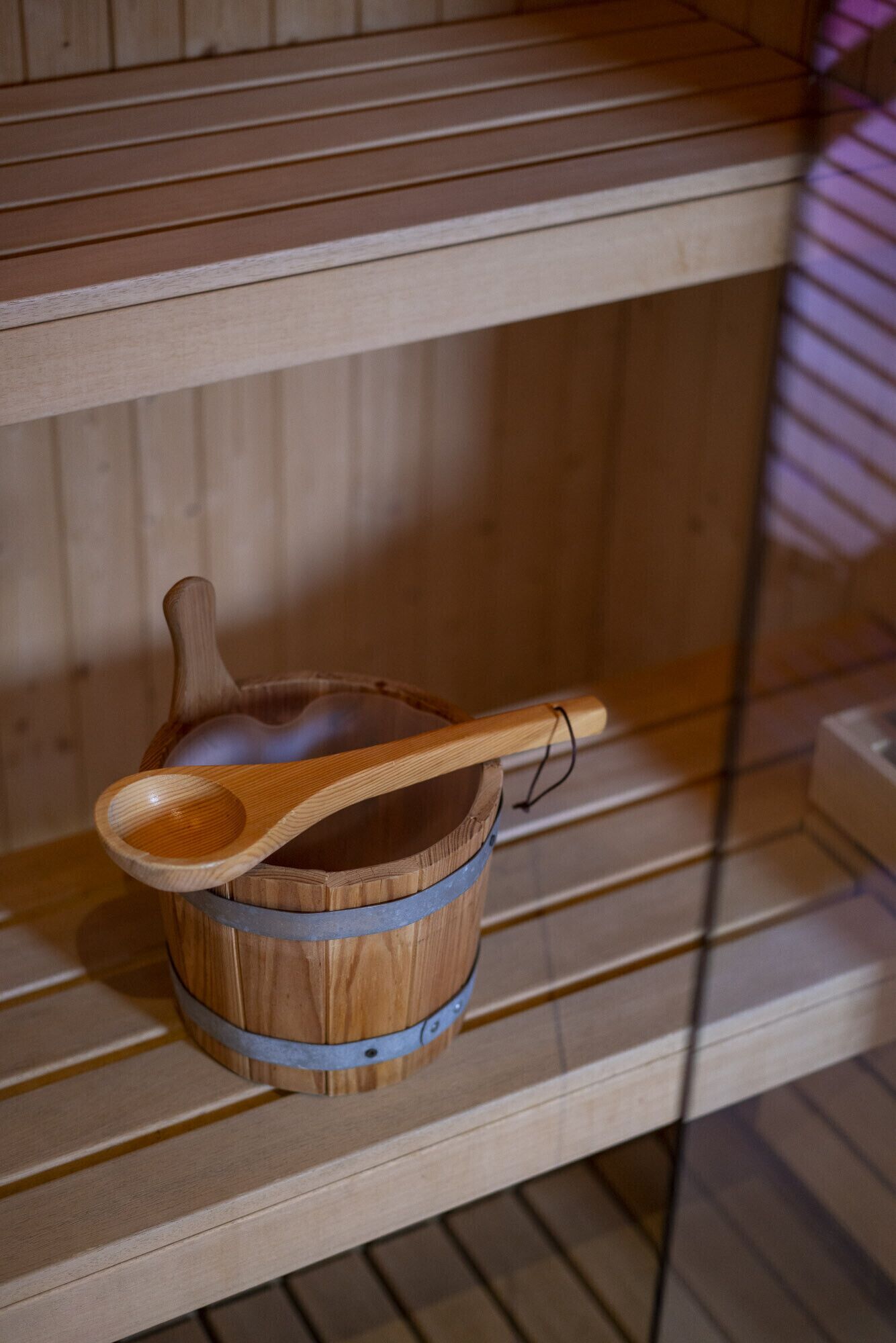 A wooden bucket with a wooden scoop on a shelf.