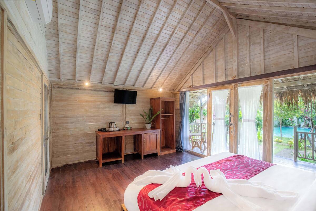 A wooden room with a bed, a desk, and a TV.