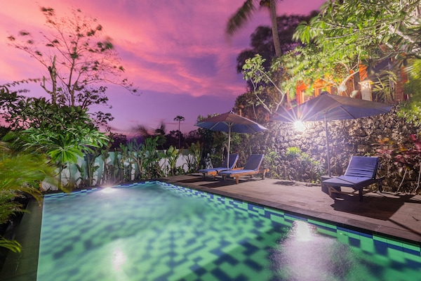 Alberca al aire libre, sombrillas en la alberca y camastros