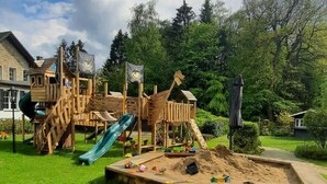 Un parque infantil con tobogán, estructuras para escalar y un arenero.