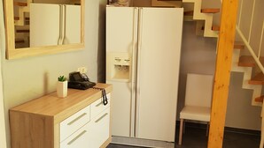 Una cocina compacta con cubierta de madera, un refrigerador blanco y un horno empotrado.