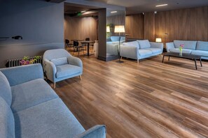 A modern living room with a sofa, armchairs, a coffee table, and a lamp. - Hostal Opera Ramblas (Barcelona)