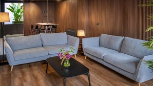 A modern living room with two grey sofas, a black coffee table, and a potted plant.