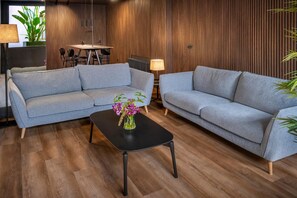 A modern living room with two grey sofas, a black coffee table, and a potted plant.