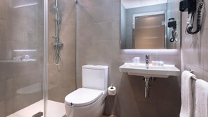 A modern bathroom with a toilet, shower, and sink.