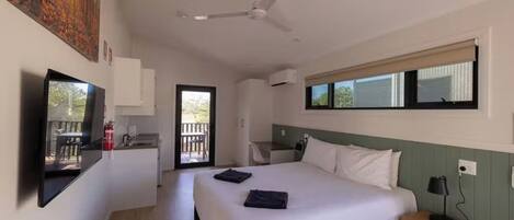 Habitación de hotel con cama, escritorio, silla, ventana y ventilador de techo.