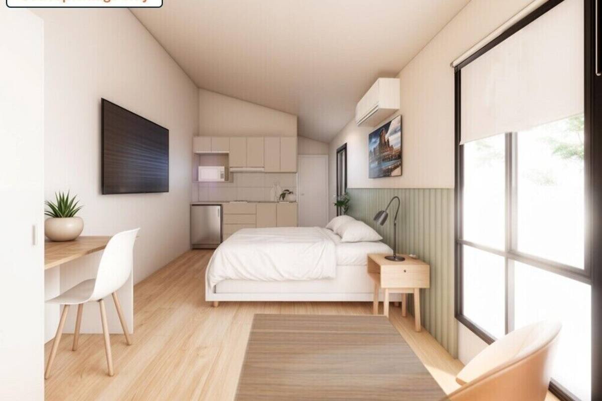 Une chambre compacte comprenant un lit, une table de chevet, une chaise, un bureau et une petite kitchenette.