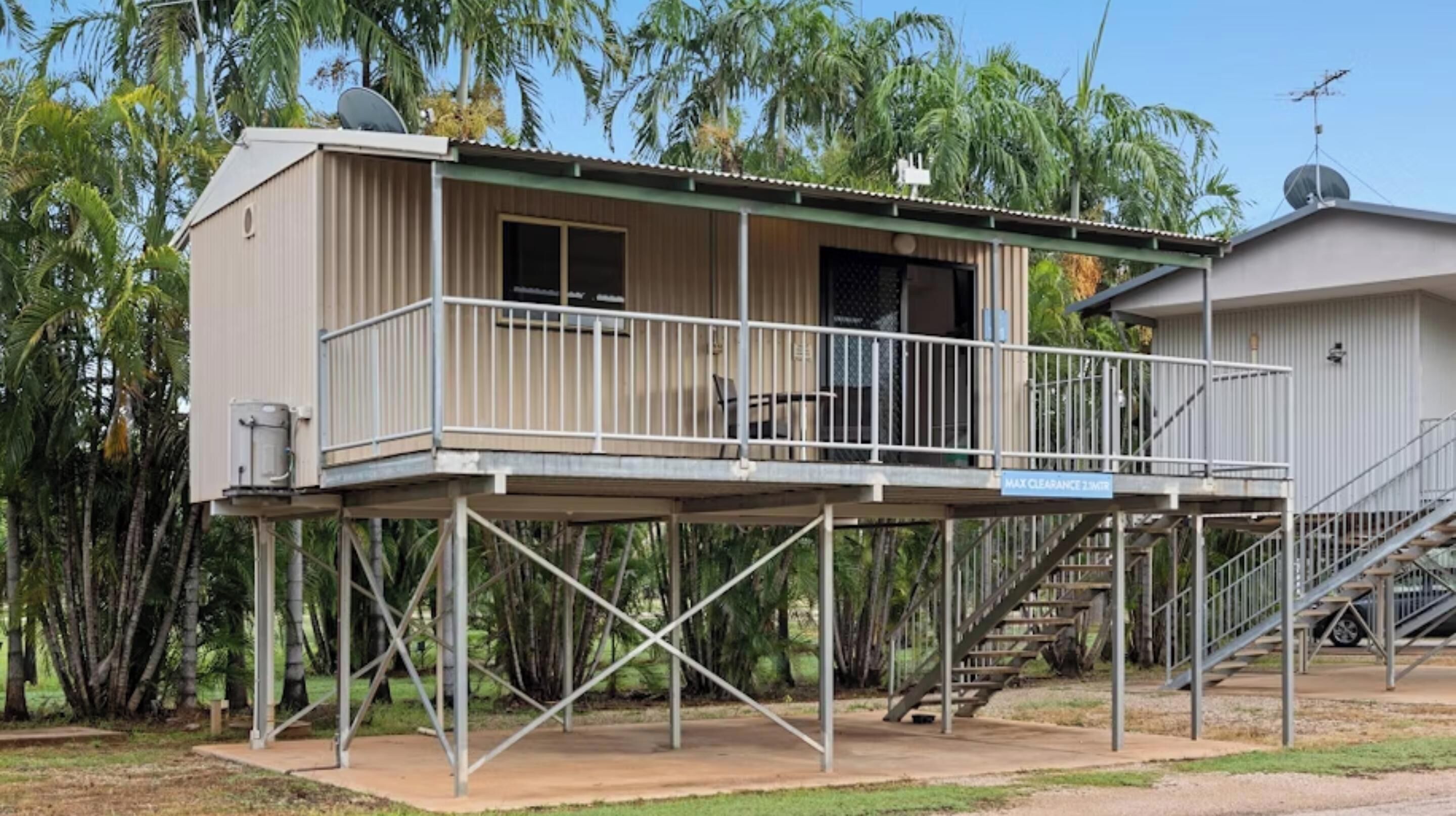 Un immeuble de deux étages doté d’un balcon, d’une antenne parabolique et d’un escalier.