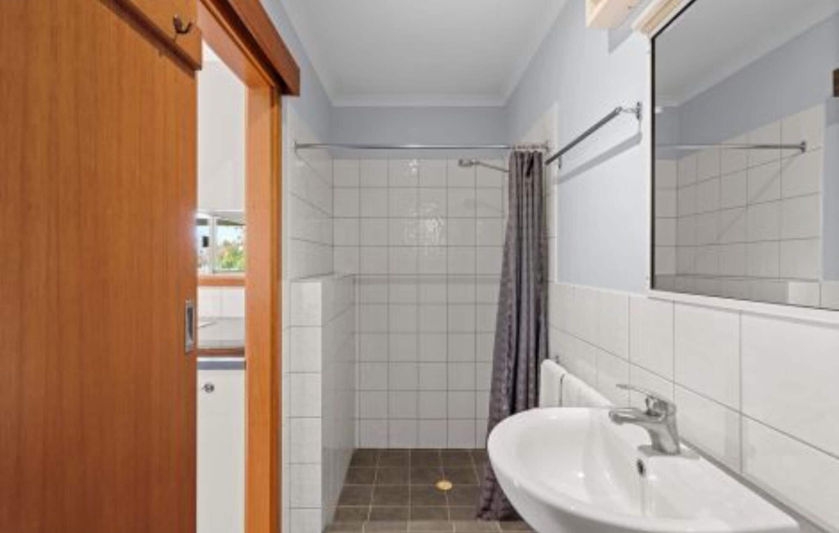 A bathroom with a shower, a sink, and a mirror.