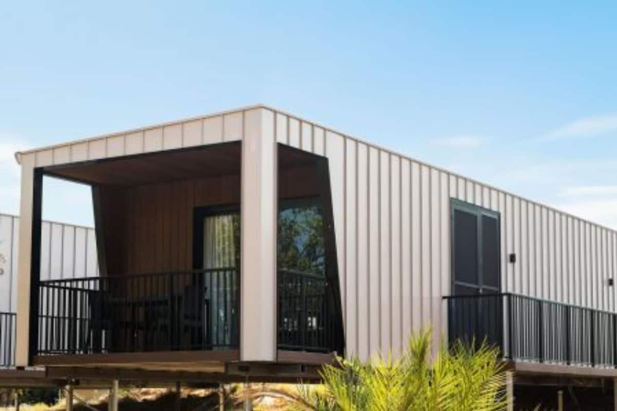 Un bâtiment moderne, de plain-pied, doté d’un toit plat, de grandes fenêtres et d’un balcon avec des garde-corps noirs.