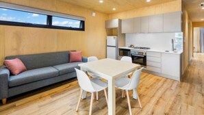 Un espacio habitable compacto con sofá, mesa de comedor y kitchenette.