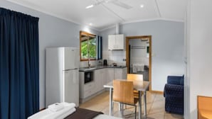A compact hotel room with a kitchenette, a dining area, and a small seating space. - Discovery Parks - Katherine (Lansdowne)
