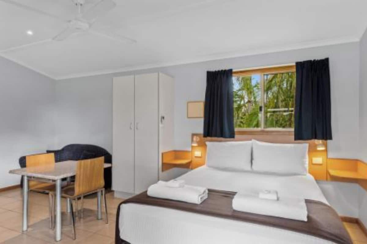 Une chambre d’hôtel avec un lit, des tables de chevet, un bureau et une chaise.