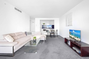 Uma sala de estar moderna com sofá, mesa de centro e painel para TV.