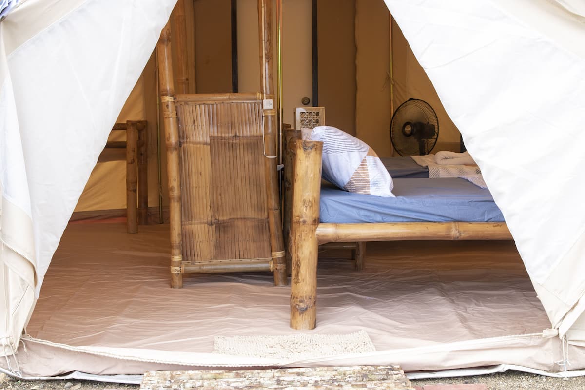 Ein Zelt mit einem Bett, einem Holzschrank und einem Ventilator.