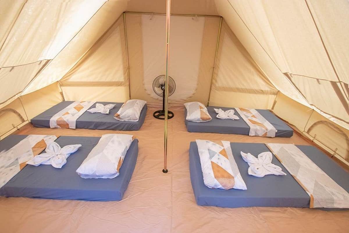 Ein Zelt mit vier Betten, jedes mit Handtuch und Decke.