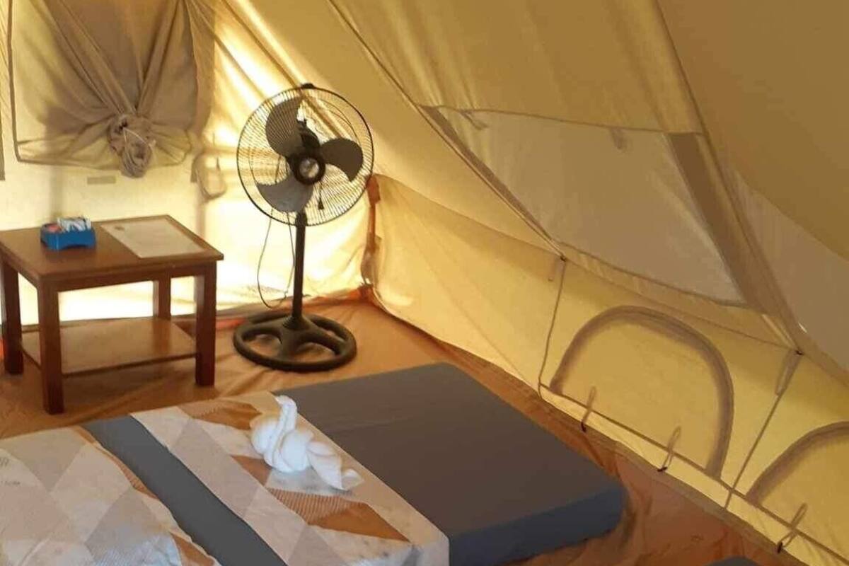 Ein Zelt mit zwei Schlafmatten, einem Tisch und einem Ventilator.