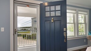 A blue door with a white handle, a window with a white frame, and a view of a house and a pool. - Luxury Monument Beach Villa /Short term rentals (Bourne)